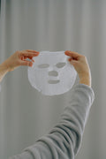 Mains tenant un masque tissu bio-collagène — soin repulpant LUMÆE
