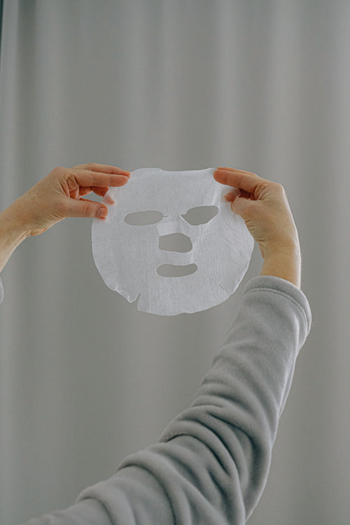 Mains tenant un masque tissu bio-collagène — soin repulpant LUMÆE
