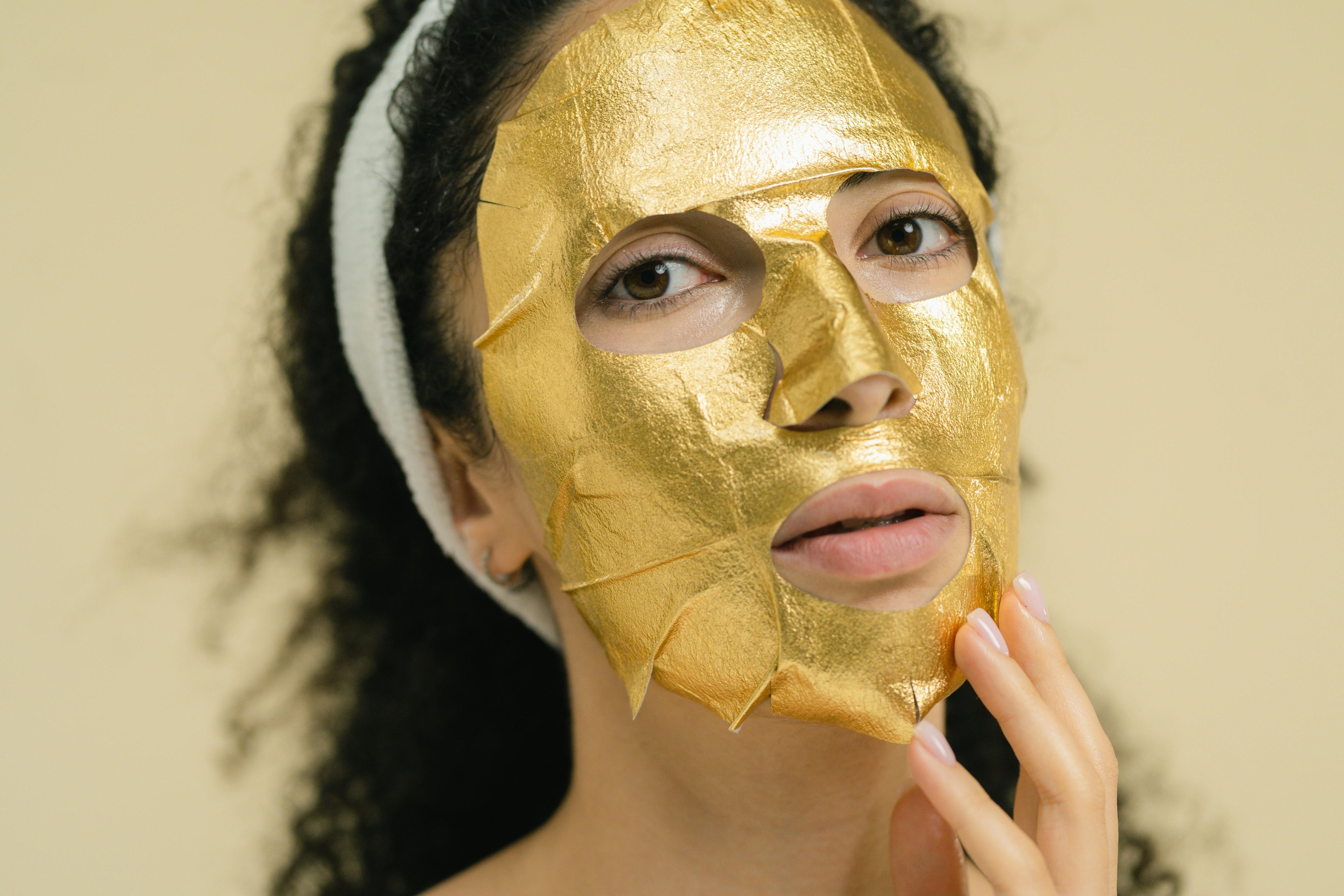 Masque tissu doré appliqué sur le visage — rituel beauté LUMÆE